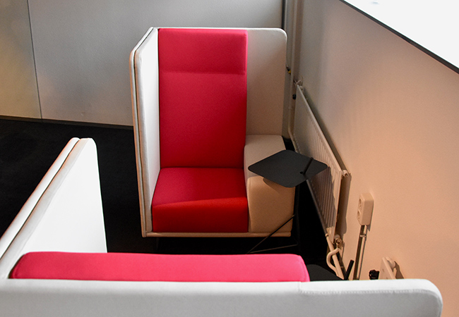 Twee 1st Class 1-zits banken tegenover elkaar in de open kantoorruimte.