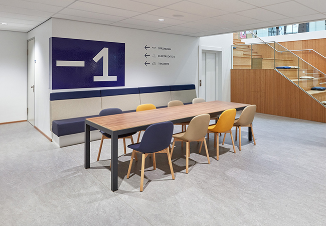 Souterrain/wachtruimte van sportaccommodatie SportQube ingericht met fraaie Slick tafel met Artifort Beso stoelen.